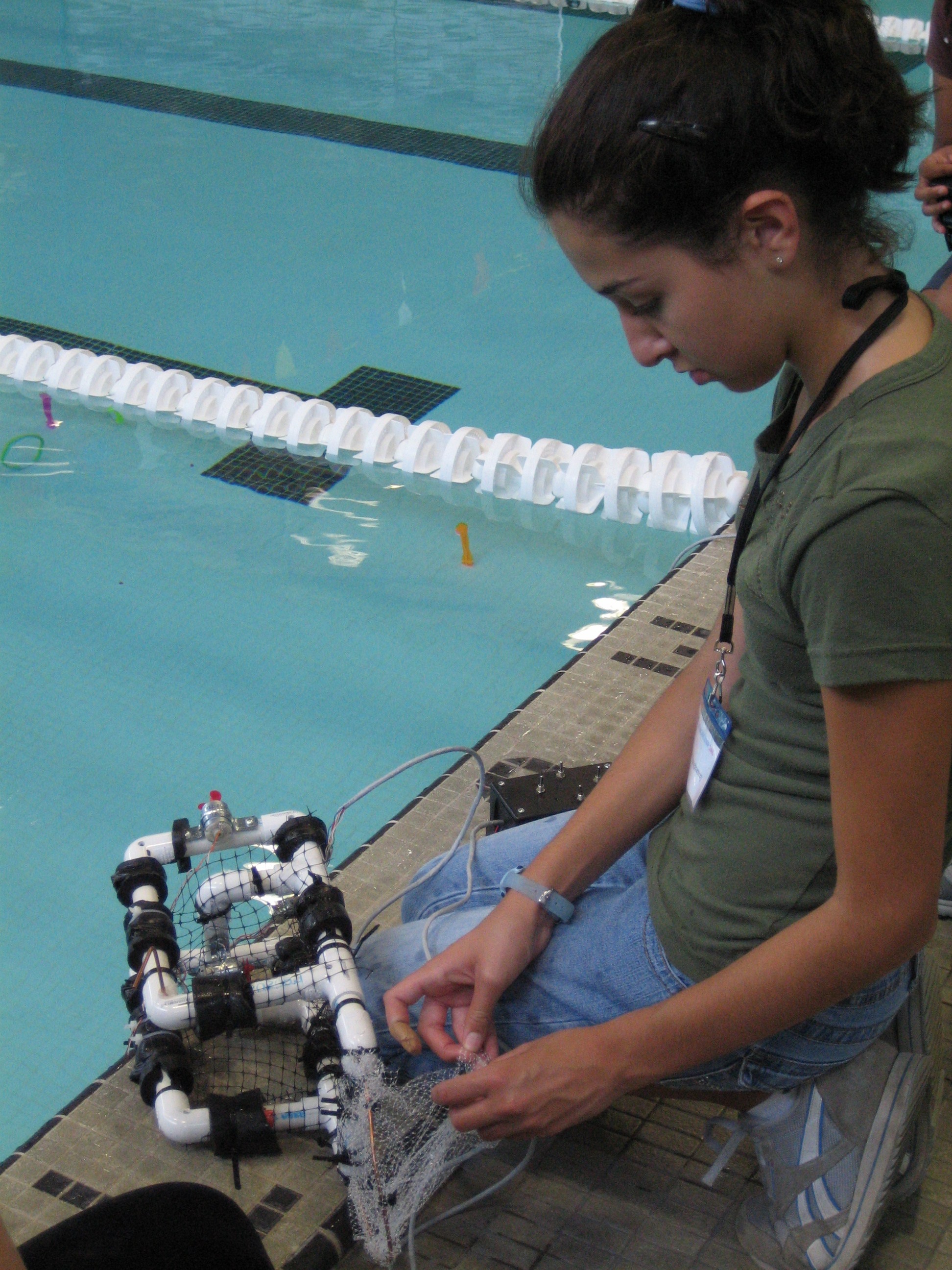 girl at poolside preparing submarine for testing